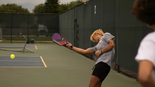 A woman hitting a ball with a paddle racquet